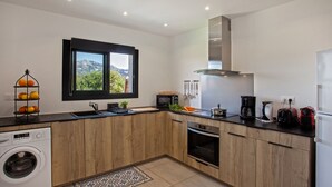 A modern kitchen with wooden cabinets, a built-in oven, a microwave, and a coffee maker. - apart Levante shared swimming pool, bbq (Calenzana)