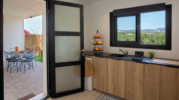 A modern kitchen with a wooden countertop, a black-framed window, and a fruit rack.