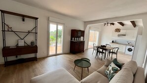 A spacious living area with a sofa, a coffee table, and a dining table with chairs. There is a kitchen area with a washing machine and a dining table. - Sea view villa (Corbara)