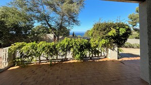 A covered patio with brick flooring, a view of the sea, and surrounding greenery. - Sea view villa (Corbara)