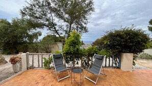 An outdoor patio with two reclining chairs, a small table, and a potted plant. - Sea view villa (Corbara)
