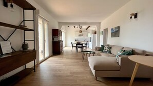 A modern living room with a sofa, a coffee table, and a dining area with chairs and a table. - Sea view villa (Corbara)