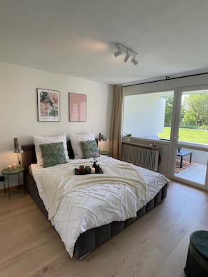 Un dormitorio espacioso con una cama grande, vistas al exterior y un radiador.