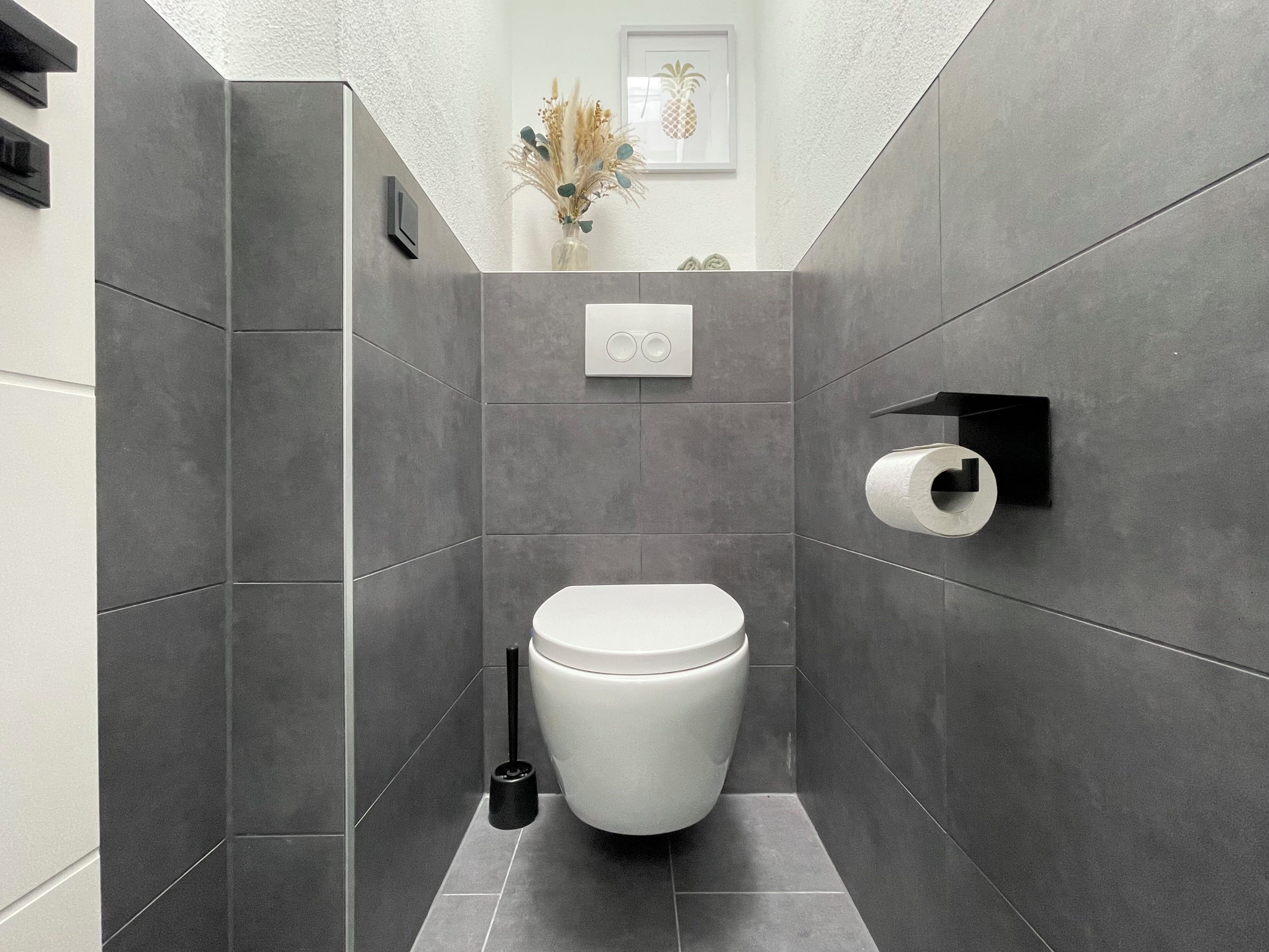A modern bathroom with a toilet, a toilet paper holder, and a hand dryer.