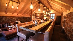 A long wooden bar with high stools, a stone wall, and hanging light bulbs. - Chalet, balcony, parking, tv, ski locker, 130m², Valloire (Valloire)