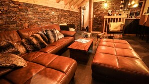 A cozy living room with a leather sofa, a wooden coffee table, and a stone wall. - Chalet, balcony, parking, tv, ski locker, 130m², Valloire (Valloire)