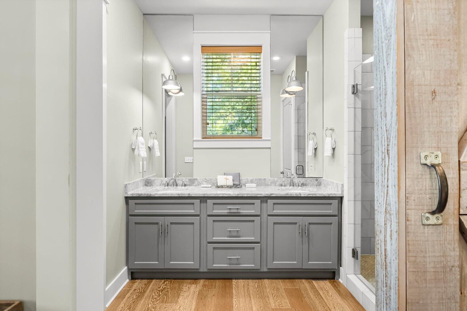 A modern bathroom with a large vanity, two sinks, and a window with blinds.