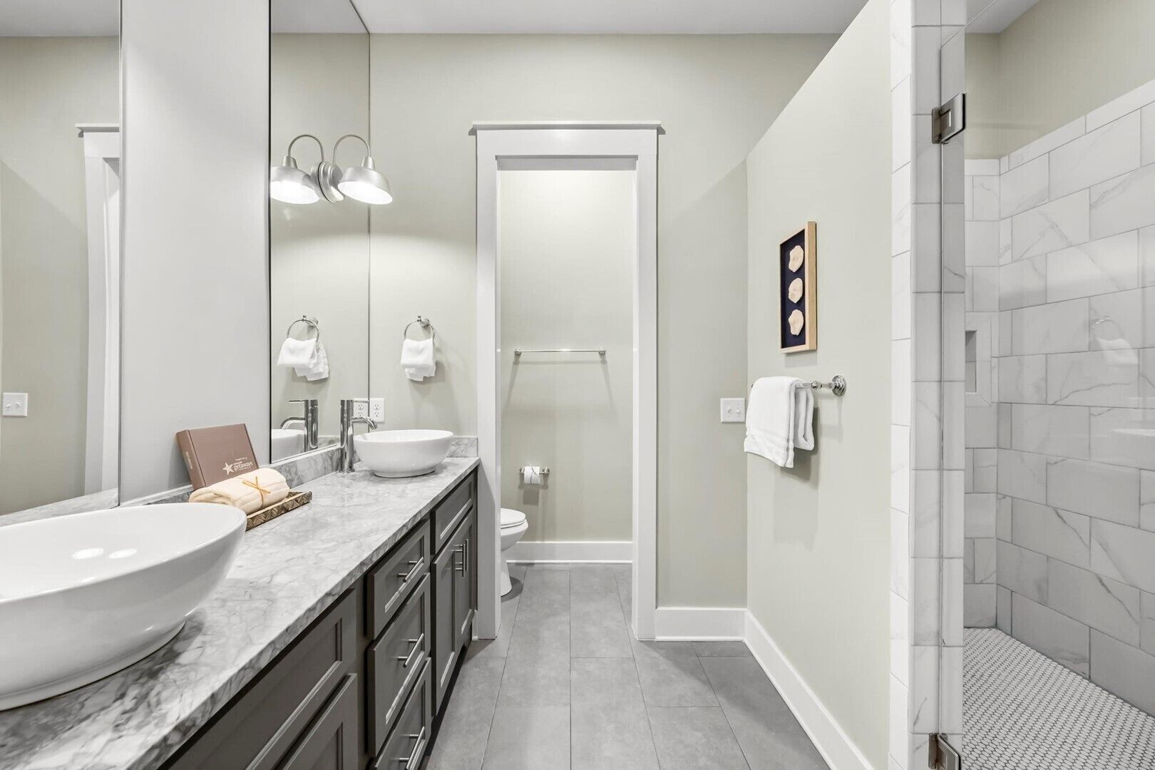 A modern bathroom with a large white sink, a mirror, and a shower area.