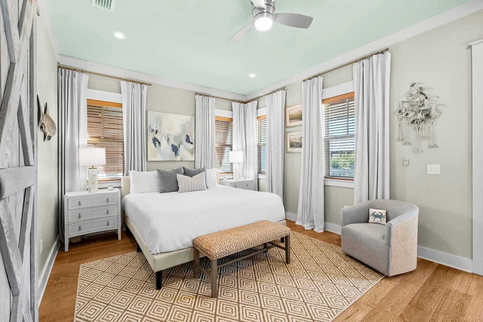 A bedroom with a bed, bedside tables, a bench, a chair, and a ceiling fan.