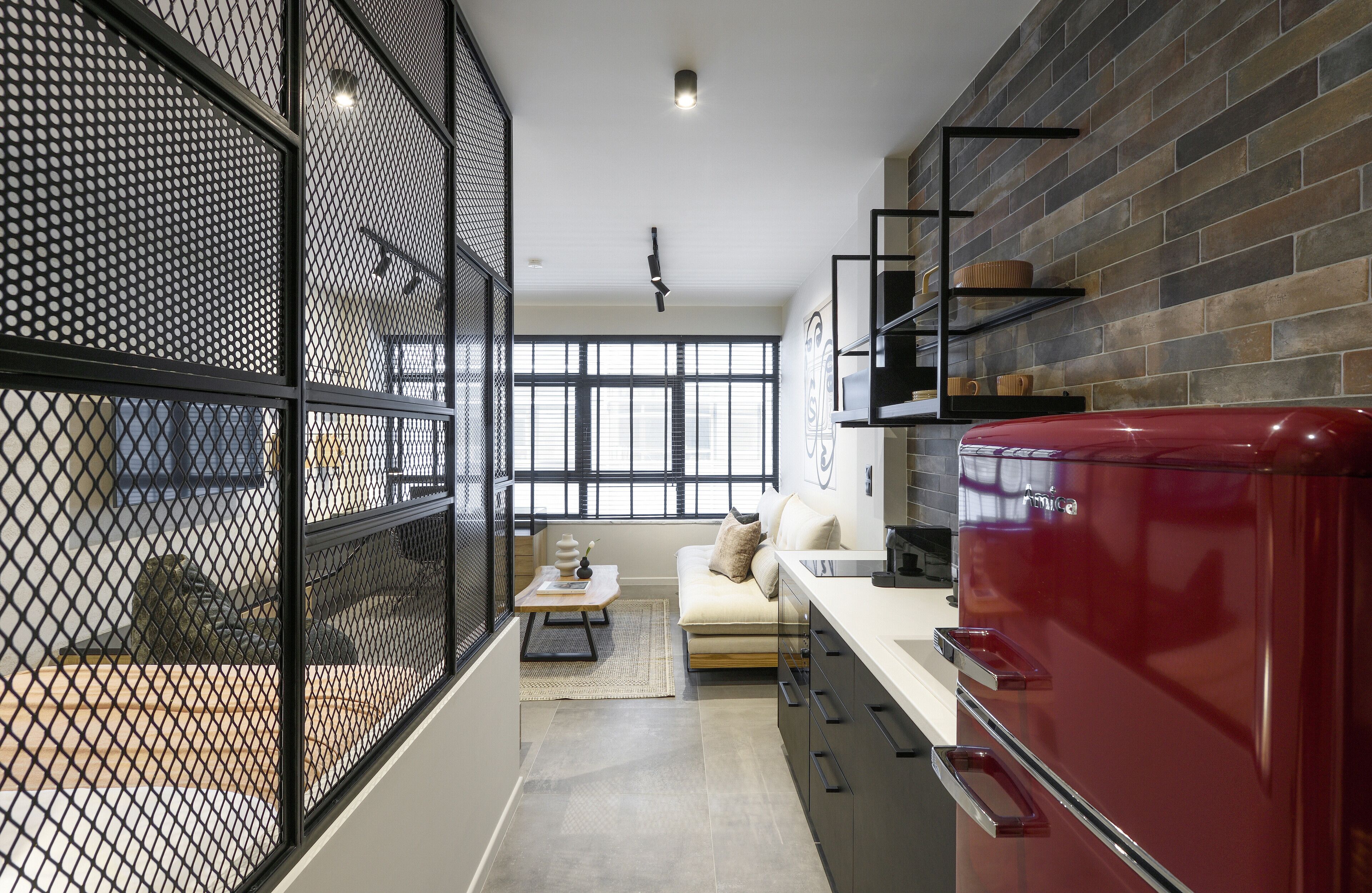 A modern kitchen with a red refrigerator, black shelving, and a large window.