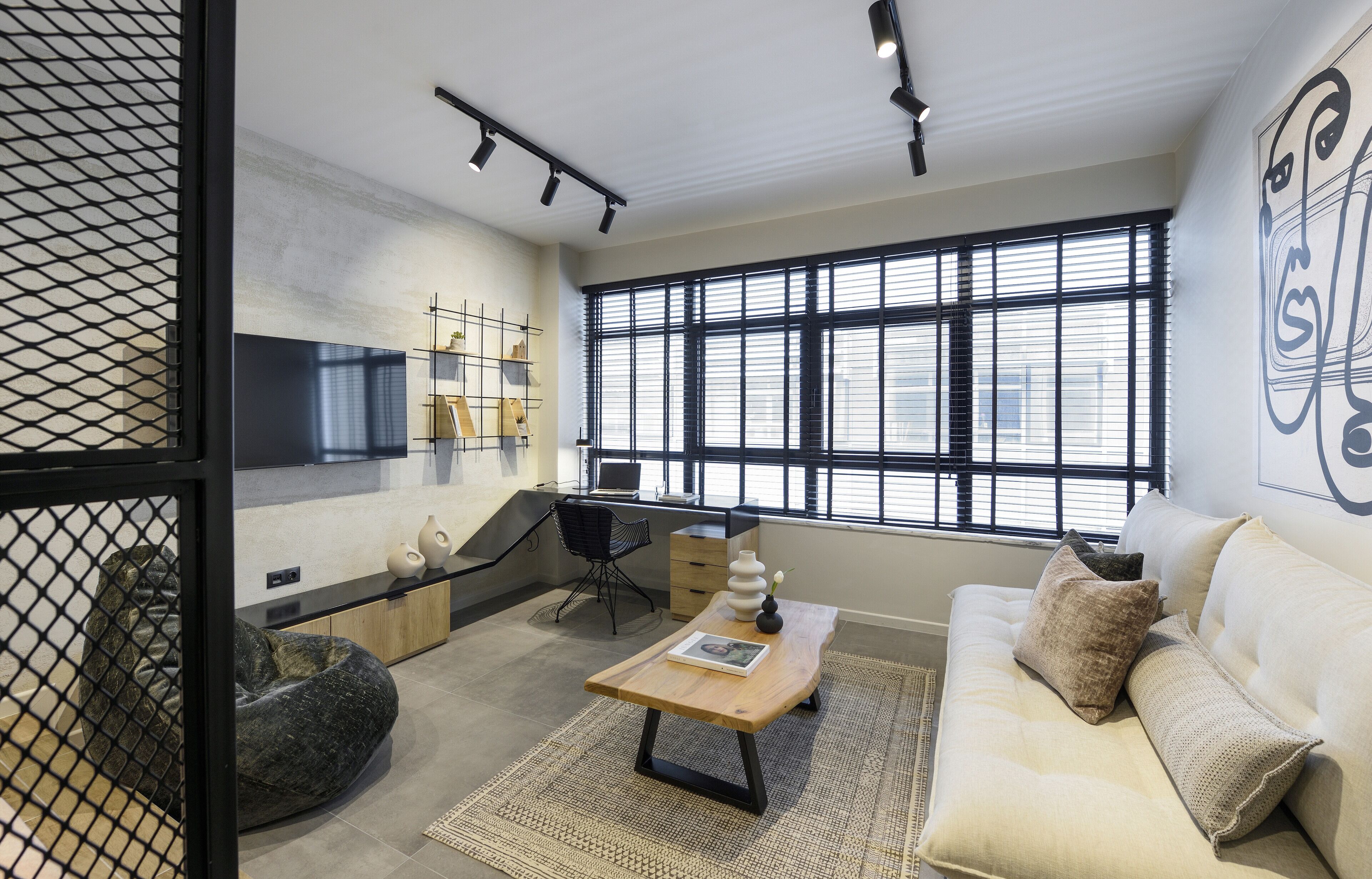 A modern living room with a sofa, coffee table, and a large window with blinds.