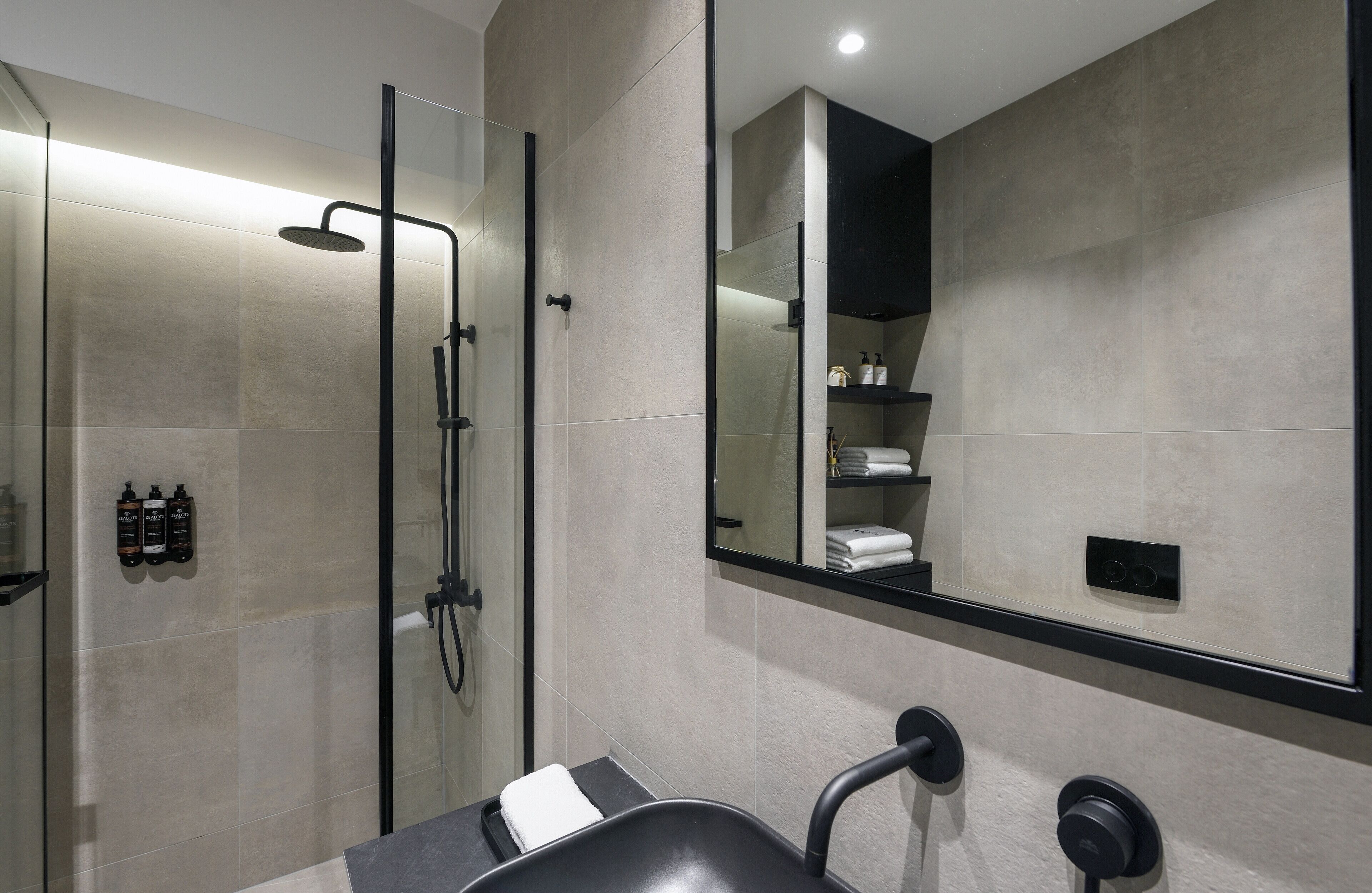 A modern bathroom with a glass-enclosed shower, a large mirror, and a black sink.