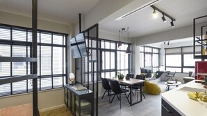 A modern interior with a dining area, kitchen, and large windows. - Olvios Lofts Ladadika (Thessaloniki)