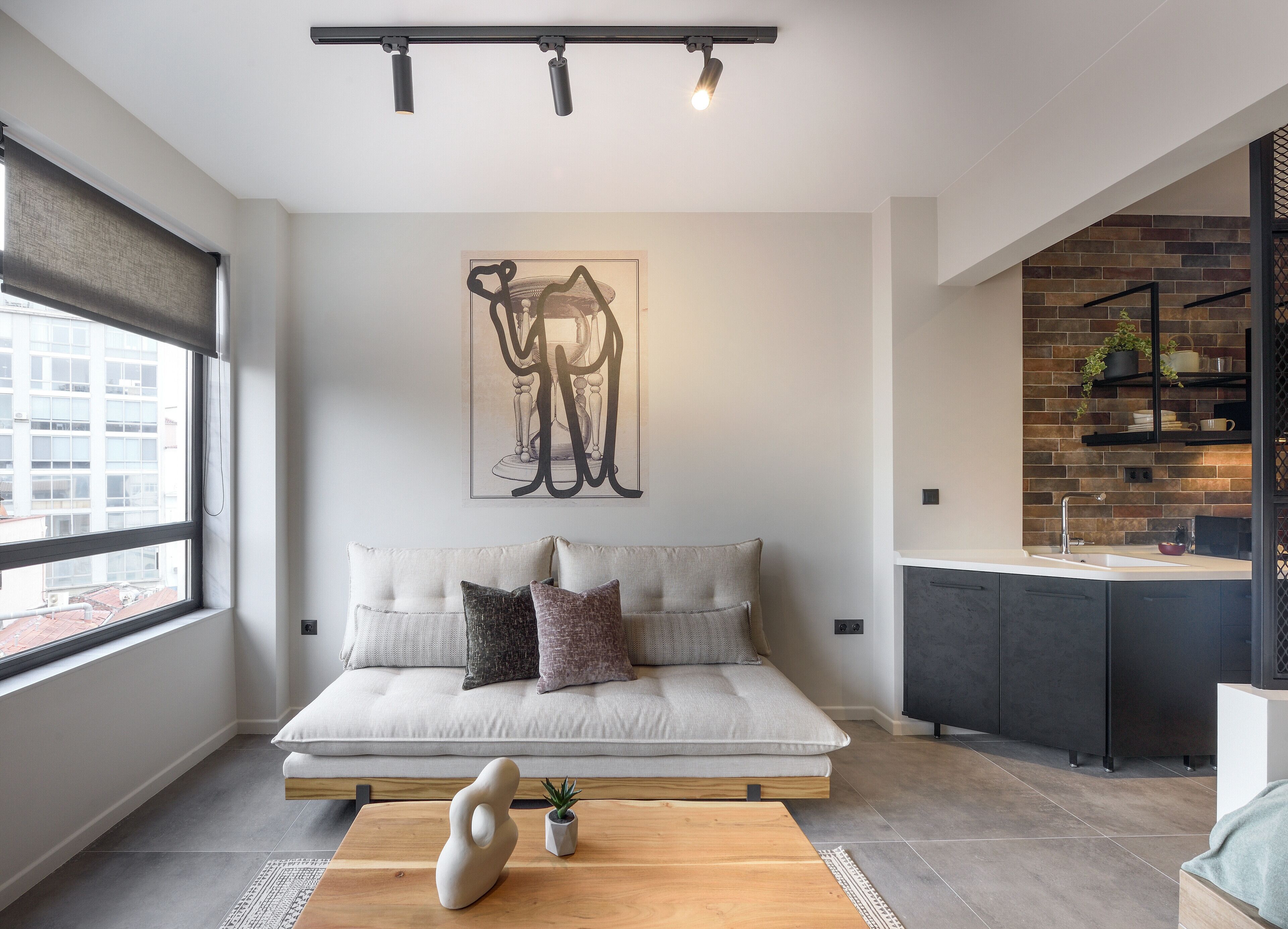 A modern living room with a sofa, a coffee table, and a kitchen area with a sink and shelves.