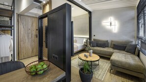 A modern living room with a sofa, a coffee table, and a dining area with a basket of apples. - Olvios Lofts Ladadika (Thessaloniki)