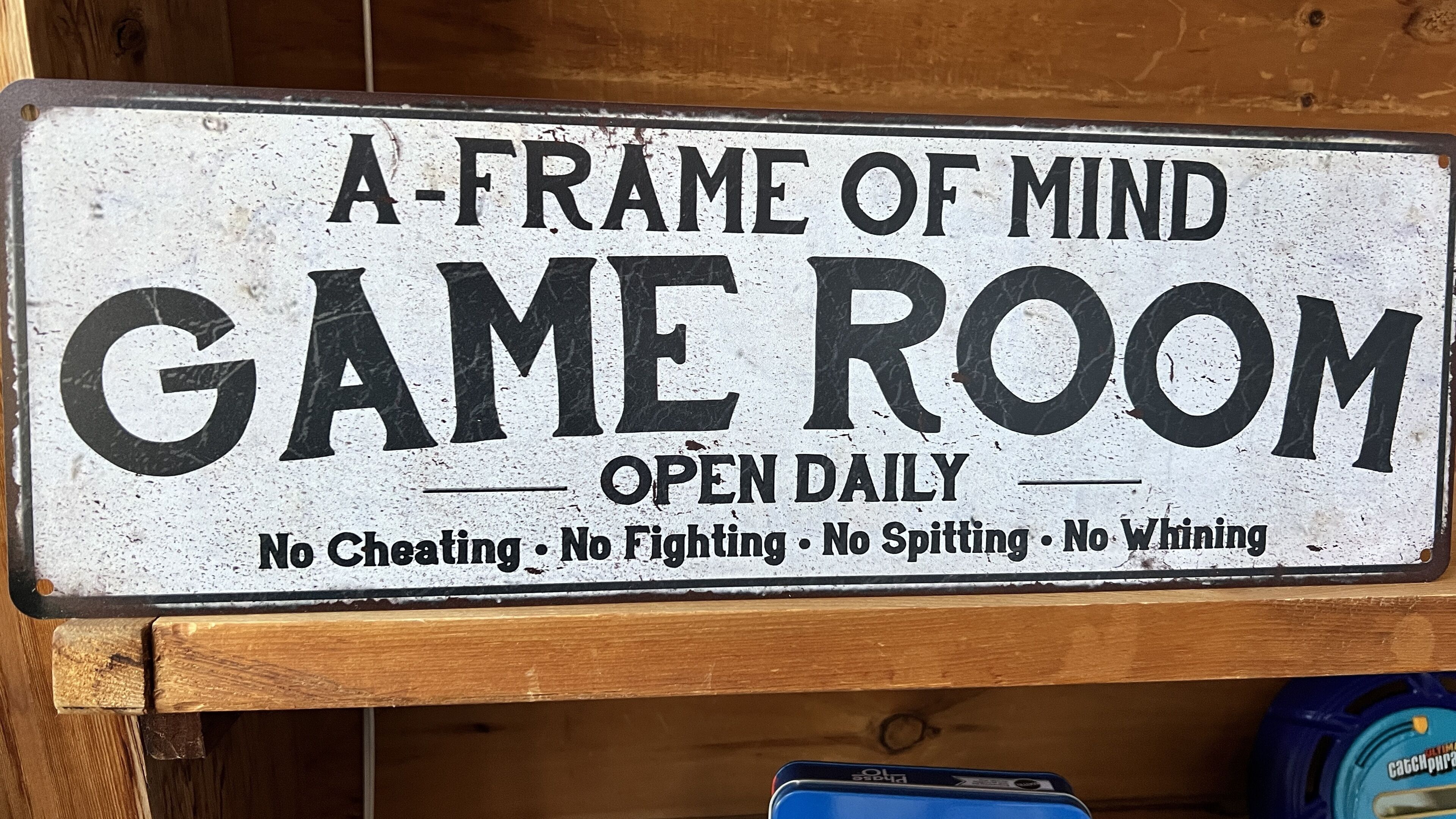 A sign for a game room with rules: no cheating, fighting, spitting, or whinging.