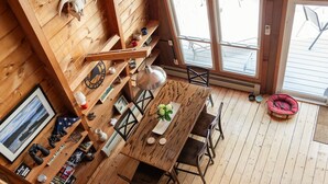 Ein Holzinterieur mit Esstisch, Stühlen, einer Hängelampe und einem Haustierbett.