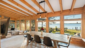 Ruime kamer met een grote houten eettafel, zwarte stoelen en uitzicht op zee.