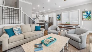 A modern living room with a sofa, armchairs, a coffee table, and a dining area. - 30A Beach House - Beach Ready By Panhandle Getaways (Panama City Beach)