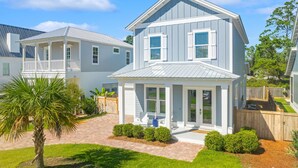 A two-story house with a covered porch, a fenced yard, and a palm tree. - 30A Beach House - Beach Ready By Panhandle Getaways (Panama City Beach)