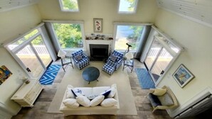Una sala de estar amplia con chimenea, dos ventanas grandes y una zona de estar acogedora con sofá y sillones.