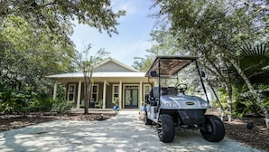 A golf cart parked in front of a house with a covered porch and a pathway leading to the entrance. - 30A Beach House - Mar Chiquita By Panhandle Getaways (Panama City Beach)