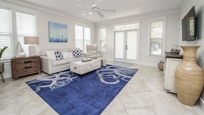 A spacious living room with a white sofa, blue and white patterned rug, and a large vase. - 30A Beach House - Mar Chiquita By Panhandle Getaways (Panama City Beach)