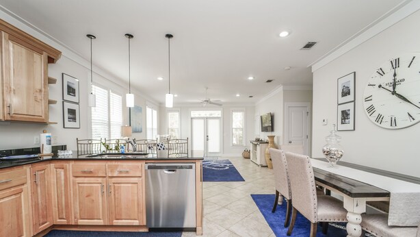 A modern kitchen with wooden cabinets, stainless steel dishwasher, and pendant lights. - 30A Beach House - Mar Chiquita By Panhandle Getaways (Panama City Beach)