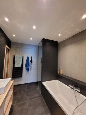 Een bad/douchecombinatie, een haardroger, handdoeken
