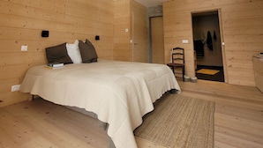 A wooden-paneled bedroom with a bed, a chair, and a small table. - Magnificent architect-designed chalet, breathtaking view of Mont Blanc (Hauteluce)