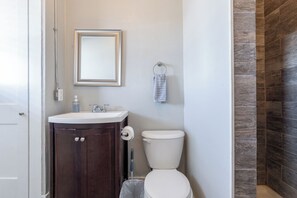 Ein Badezimmer mit Holzschrank, weißem Waschbecken, Toilette und Spiegel mit Rahmen.