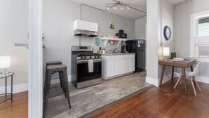 Une cuisine moderne avec des meubles blancs, une cuisinière en acier inoxydable et un réfrigérateur noir. On y trouve également un coin repas avec une table et des chaises.