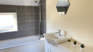 Een moderne badkamer met een bad, een wastafel en een spiegel.
