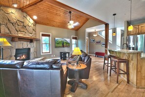 A spacious living area with a stone fireplace, leather seating, and a kitchen with a stainless steel refrigerator. - Townhouse right off Park City's Rail Trail| Managed by Park City Lodging (Park City)