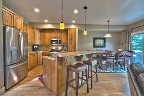 A modern kitchen with stainless steel appliances, wooden cabinets, and a central island with bar stools. - Townhouse right off Park City's Rail Trail| Managed by Park City Lodging (Park City)