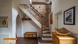 A staircase with a brick wall, wooden steps, and a metal handrail. - The Mad Hatter (London)