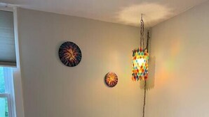A room with two upholstered chairs, a small table, and two wall-mounted decorative lights. - Main, Three Bedroom House in Historic Loveland (Loveland)