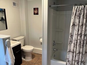 A bathroom with a toilet, sink, and shower curtain. - Main, Three Bedroom House in Historic Loveland (Loveland)