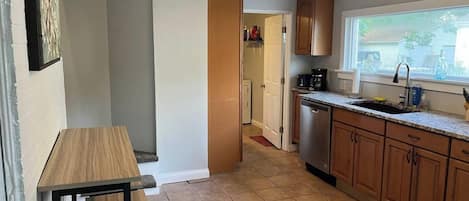 A kitchen with wooden cabinets, a countertop, a sink, and a window.