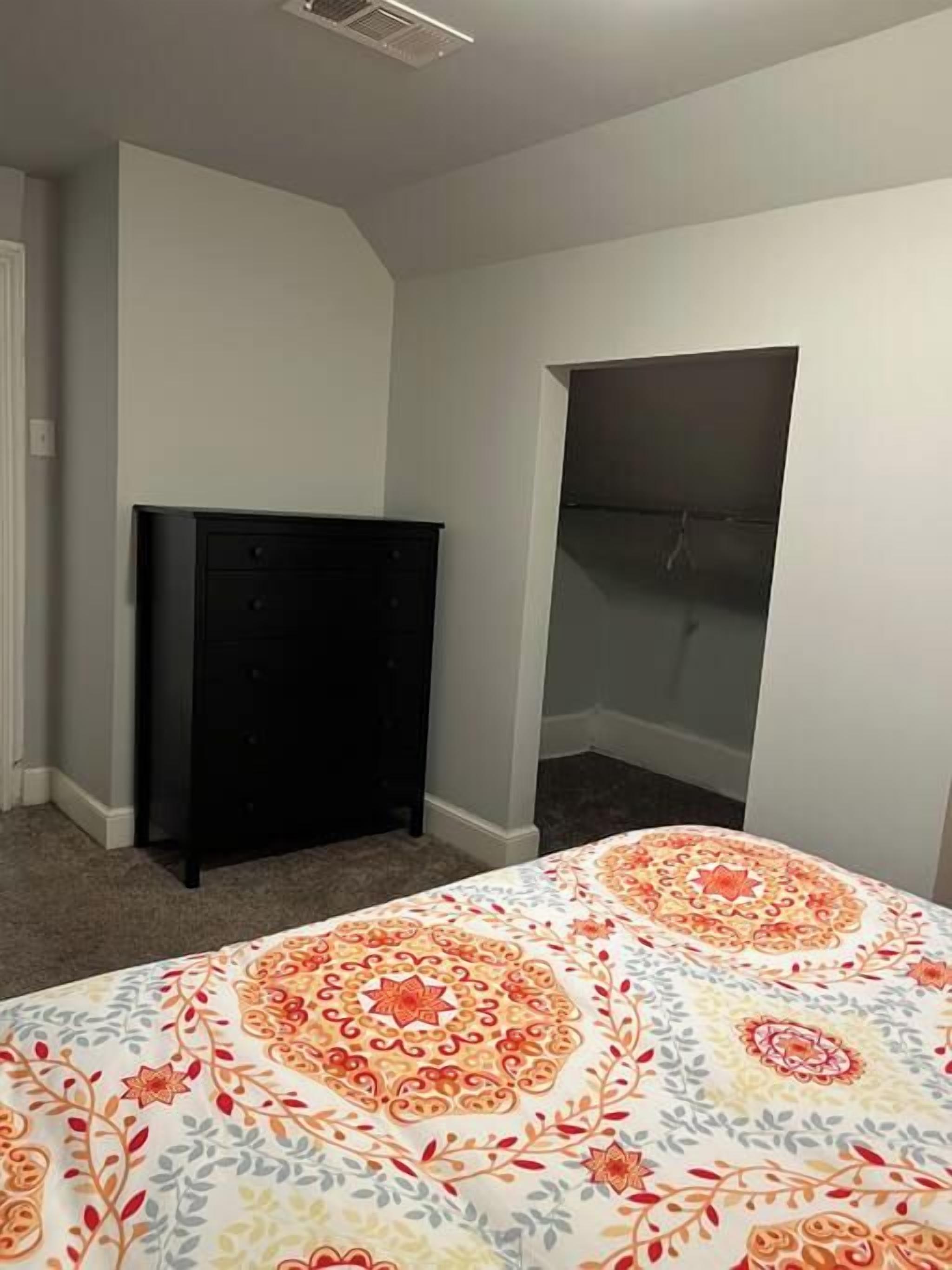 A bedroom with a bed, a dresser, and a closet.
