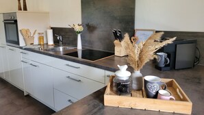 Una cucina moderna con cappa in acciaio inossidabile, forno integrato, lavello a due vasche e macchina per il caffè.