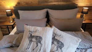 Un letto con testiera, numerosi cuscini e due abat-jour.
