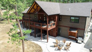 Une cabane en rondins à deux étages, dotée d’un balcon, d’un espace salon extérieur et d’un foyer.