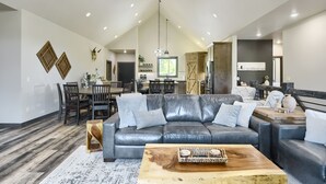 Un salon spacieux avec un canapé en cuir, une table basse en bois et un coin repas agrémenté d’un lustre.