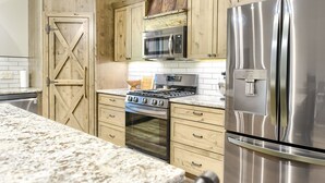 Une cuisine avec des meubles en bois, un réfrigérateur en acier inoxydable, un four à micro-ondes et une cuisinière.