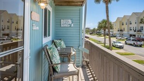 Une véranda avec deux chaises en bois et une table, une pancarte de bienvenue et un panneau indiquant que la propriété est à vendre.