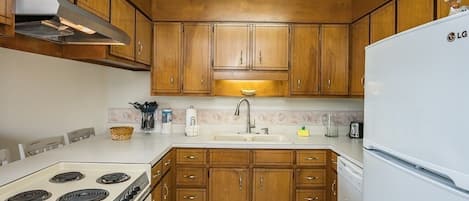 A kitchen with wooden cabinets, a white stove, and a white refrigerator.