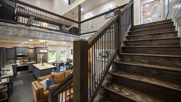 A spacious interior with a central staircase, a kitchen area, and a seating area with a sofa and chairs. - Forest Retreat Hot Tub Slide Arcade Family Fun (Broken Bow)