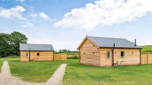 Two wooden cabins with metal roofs, a gravel path, and a grassy field. - Peep o' Day (York)