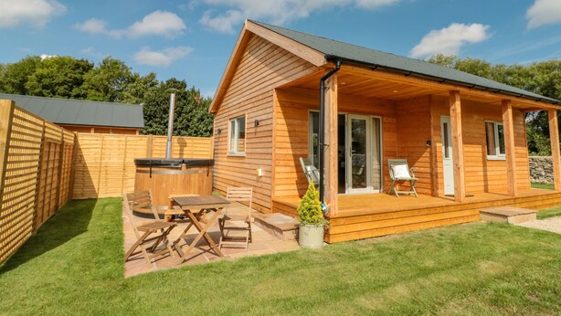 A wooden cabin with a patio area, a covered deck, and a small garden. - Peep o' Day (York)